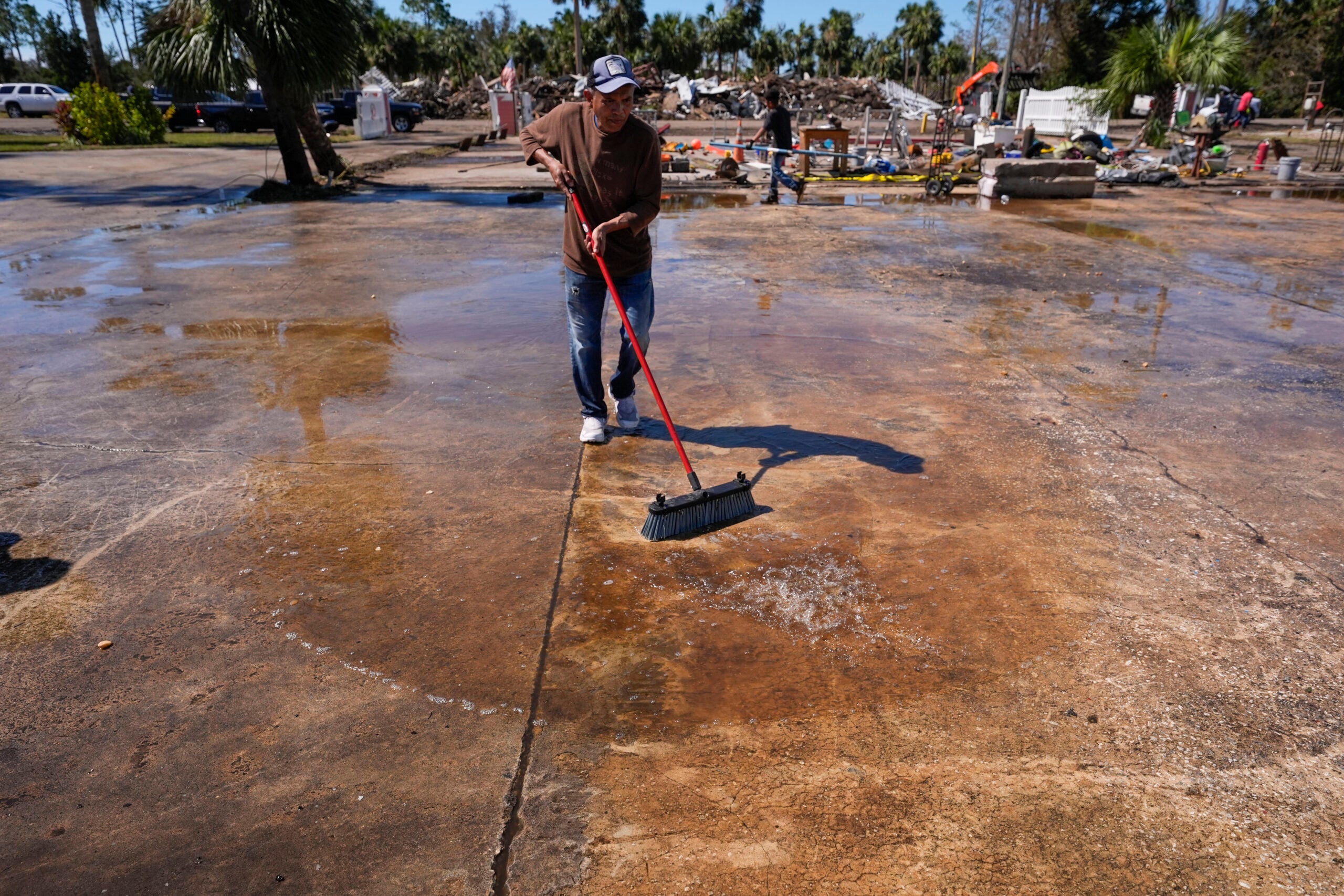 Workers clean up a dock where a boat shed was destroyed in the aftermath of Hurricane Helene, in Jena, Fla.