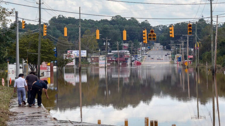 A passerby checks the water depth of a flooded road in Morganton, N.C.