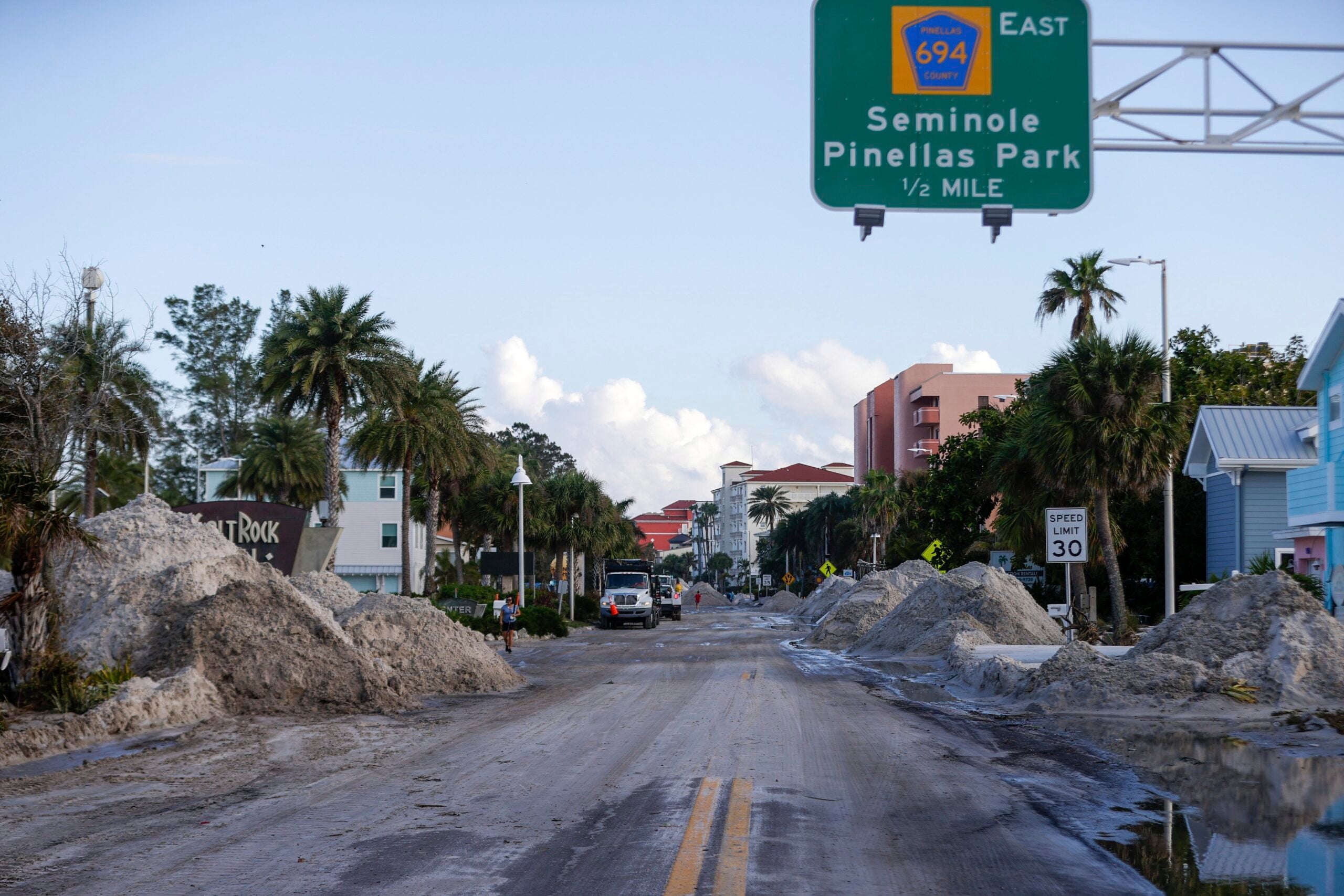 Crews work to clean up the tons of sand and debris pushed onto Gulf Boulevard from Hurricane Helene storm surge. 