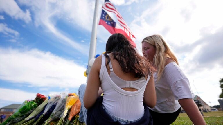 Two students view a memorial as the flags fly half-staff after a shooting Wednesday at Apalachee High School, Thursday, Sept. 5, 2024, in Winder, Ga.