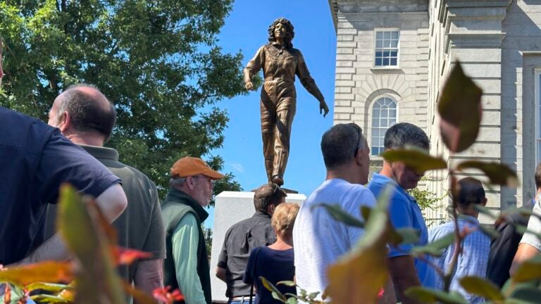 A crowd surrounds the newly-unveiled statue of Christa McAuliffe at the New Hampshire Statehouse, Monday, Sept. 2, 2024, in Concord, N.H.