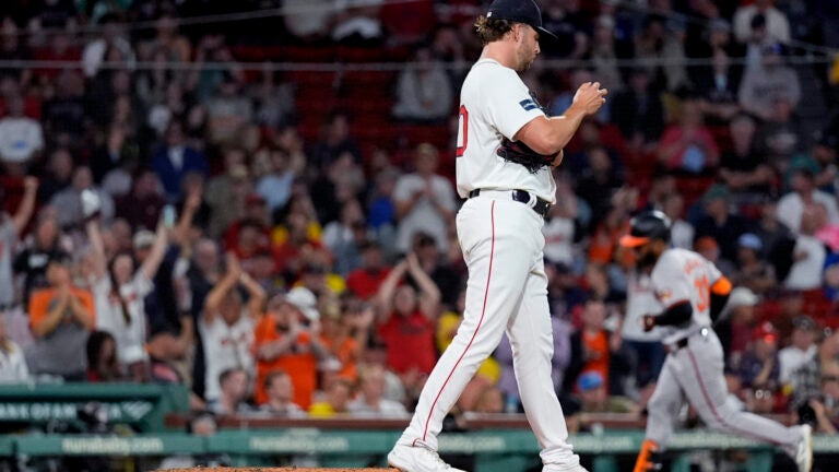 Red Sox pitcher Kutter Crawford prepares a fresh baseball as Baltimore Orioles' Cedric Mullins rounds the bases, on his two-run home run, during the third inning.