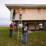 Jerry McCullen, top of ladder left, and Carson Baze, top of ladder right, put plywood over the windows of a house ahead of Hurricane Helene, expected to make landfall Thursday evening, in Alligator Point, Fla., Wednesday, Sept. 25, 2024.