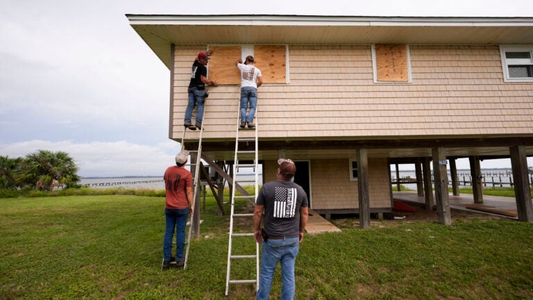Jerry McCullen, top of ladder left, and Carson Baze, top of ladder right, put plywood over the windows of a house ahead of Hurricane Helene, expected to make landfall Thursday evening, in Alligator Point, Fla., Wednesday, Sept. 25, 2024.