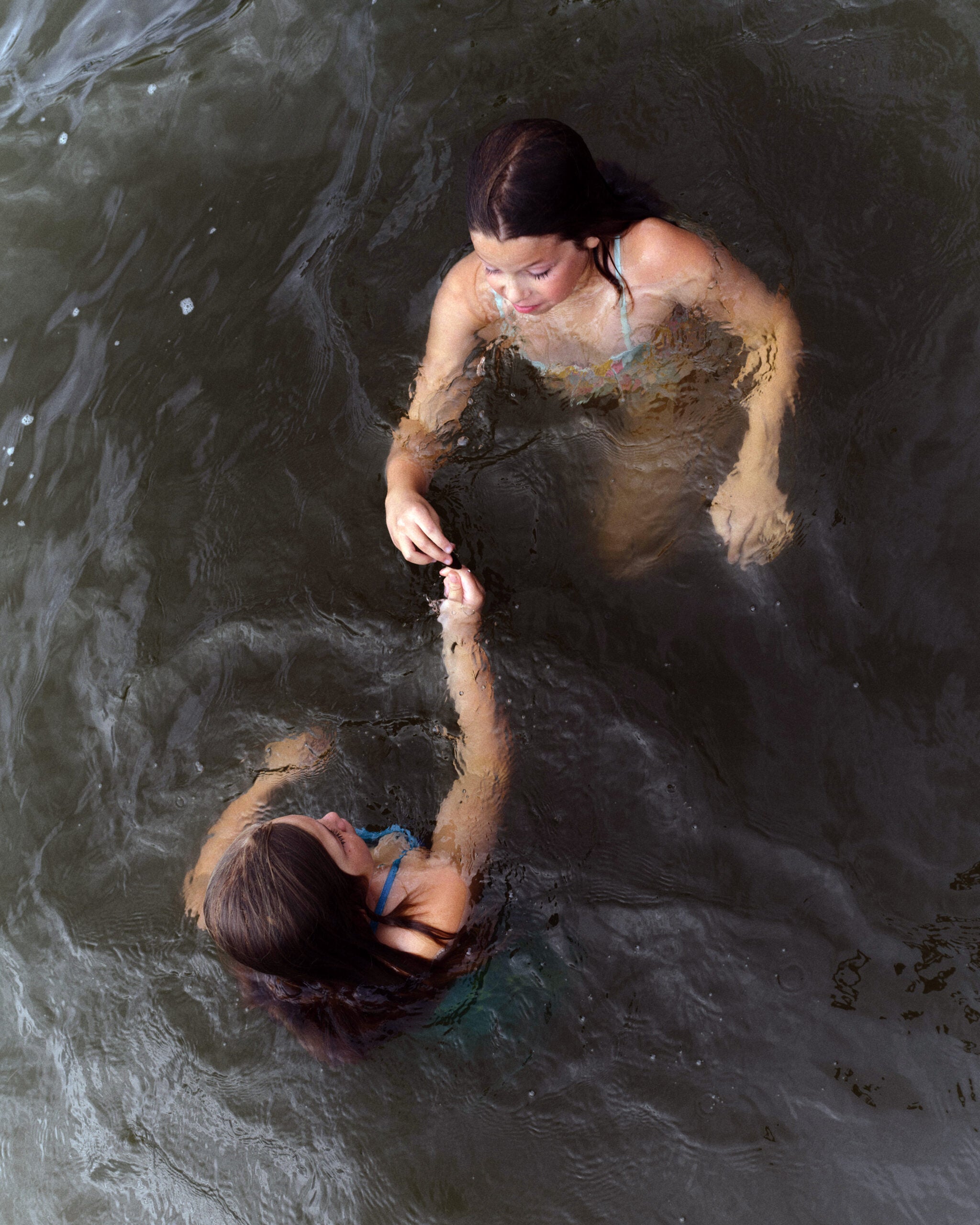 Two girls swim in the lake while attending Pine Creek Camp's Dirigo Experience.