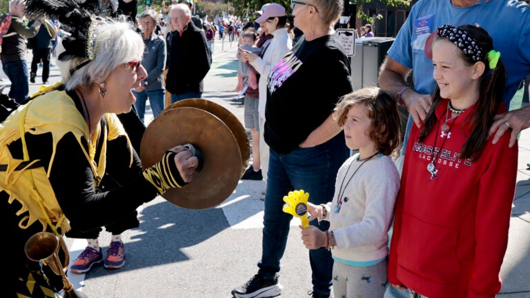 A band member of the Honk Fest Parade greets young spectators as they make their way towards Harvard Square.