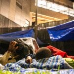 Beatrice Destine, 42 (left), lays down next to her 5 children at the Wollaston T stop as people sleep outside it in Quincy, Massachusetts on Monday night, Aug. 26, 2024. The family are Haitian migrants.