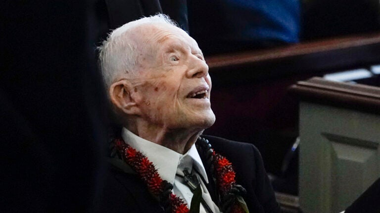 Former President Jimmy Carter greets attendees as he departs the funeral service for his wife.