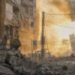 A man runs for cover as a smoke raises in the background following an Israeli airstrike in Dahiyeh, Beirut, Lebanon.