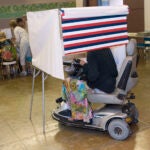 A woman in a motorized wheelchair casts her vote at the Waikiki Community Center in Honolulu.