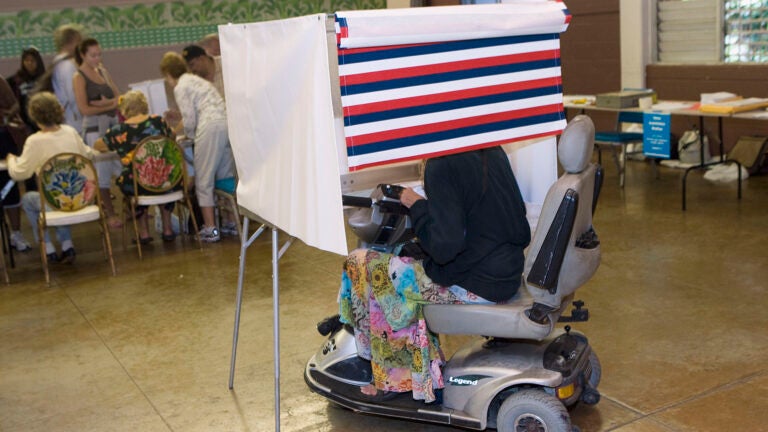 A woman in a motorized wheelchair casts her vote at the Waikiki Community Center in Honolulu.