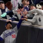 Fans interfere with a foul ball caught by Los Angeles Dodgers right fielder Mookie Betts during the first inning in Game 4 of the baseball World Series against the New York Yankees, Tuesday, Oct. 29, 2024, in New York.