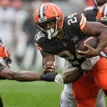 Cleveland Browns running back Nick Chubb (24) is pressured by Cincinnati Bengals safety Dax Hill, left, during an NFL football game, Sept. 10, 2023, in Cleveland.