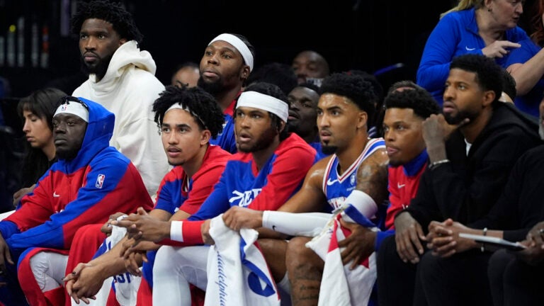 Joel Embiid and Paul George watch a 76ers-Bucks game from the bench.