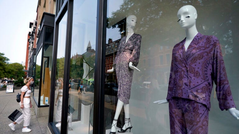 A person passing by on the left enters a clothing store in Boston's Newbury Street shopping district.