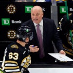 Boston Bruins head coach Jim Montgomery, center, talks to left wing Brad Marchand (63) in the third period. The Bruins fall to the Hurricanes, 3-2, at TD Garden.