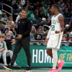 Joe Mazzulla speaks with Lonnie Walker IV, who walks to the team bench.