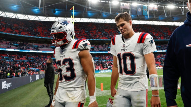 Drake Maye and Christian Elliss walk off the field after falling to the Jaguars.