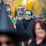 A costumed reveler dressed as Frankenstein's monster walks among people in Salem.