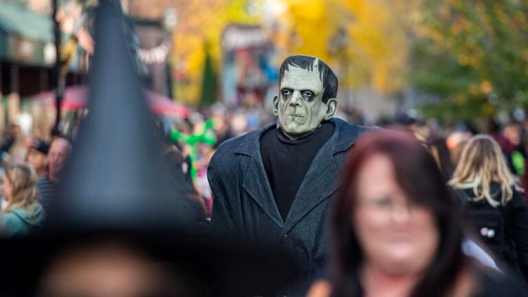 A costumed reveler dressed as Frankenstein's monster walks among people in Salem.
