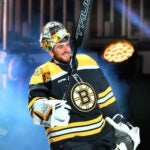 Fans try to get the attention of Boston Bruins goaltender Jeremy Swayman (1) takes to the ice through fog and lights in a pregame introduction ceremony.
