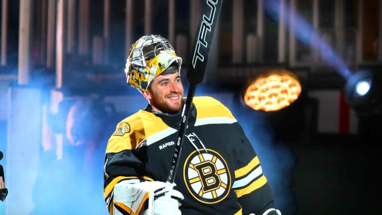 Fans try to get the attention of Boston Bruins goaltender Jeremy Swayman (1) takes to the ice through fog and lights in a pregame introduction ceremony.