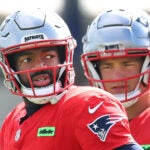 Foxborough10/02/2024 The patriots held practice on the Gillette Stadium practice field. Qb Drake Maye peers over qb Jacoby Brissett during a passing drill.