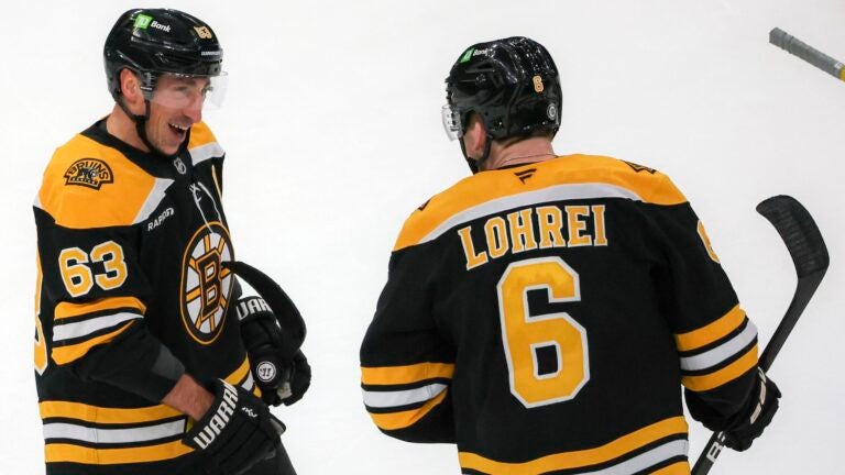 Boston Bruins left wing Brad Marchand (63) celebrates his game winning goal with teammate Mason Lohrei (6) against the Calgary Flames Calgary Flames during the overtime period NHL action at TD Garden.