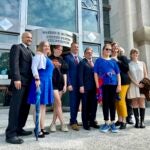 Two teens challenging New Hampshire's new law banning transgender girls from girls' sports teams, Parker Tirrell, third from left, and Iris Turmelle, sixth from left, pose with their families and attorneys in Concord, N.H., Monday, Aug. 19, 2024.