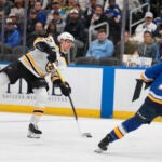 Boston Bruins' Hampus Lindholm, left, shoots past St. Louis Blues' Mathieu Joseph (71) during the first period of an NHL hockey game Tuesday, Nov. 12, 2024, in St. Louis.