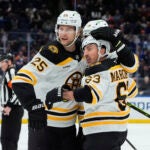 Boston Bruins left wing Brad Marchand celebrates with defensemen Brandon Carlo and Parker Wotherspoon after scoring his second goal during the first period.