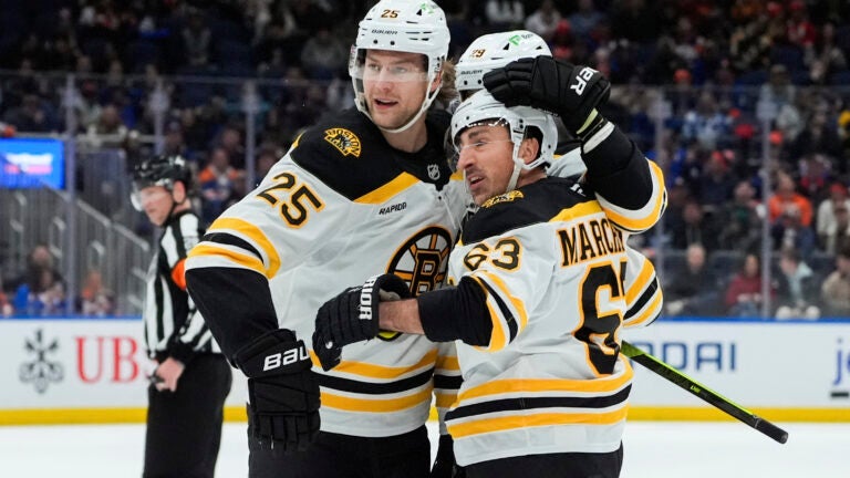 Boston Bruins left wing Brad Marchand celebrates with defensemen Brandon Carlo and Parker Wotherspoon after scoring his second goal during the first period.