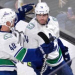 Vancouver Canucks left wing Jake DeBrusk is congratulated by Elias Pettersson after his goal against Bruins goaltender Jeremy Swayman during the second period.