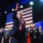 Republican presidential nominee former President Donald Trump waves as he walks with former first lady Melania Trump at an election night watch party at the Palm Beach Convention Center, Wednesday, Nov. 6, 2024, in West Palm Beach, Fla.