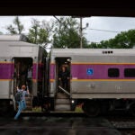 A commuter hoists herself onto an inbound train at the MBTA Fitchburg Line Commuter Rail stations in Shirley.