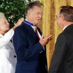 George W. Bush presents the Presidential Medal of Freedom to baseball great Ted Williams as Barbara Bush ties the medal around his neck at a White House ceremony.