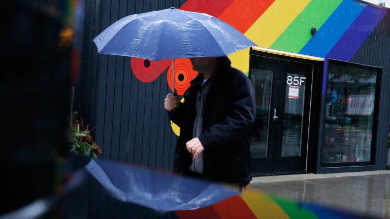 A pedestrian walks past a rainbow painted on the side of a shop as rain falls in the Seaport District. Meteorologists predict rain and possible snow on Thursday.
