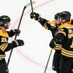 Boston Bruins left wing Brad Marchand (63) celebrates his game winning goal with teammates Elias Lindholm (28) and Charlie McAvoy (73) against the Calgary Flames Calgary Flames during the overtime period NHL action at TD Garden.