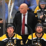 With seconds left in the game, coach Jim Montgomery stands behind Boston Bruins left wing Brad Marchand (63) and Boston Bruins center Pavel Zacha (18).