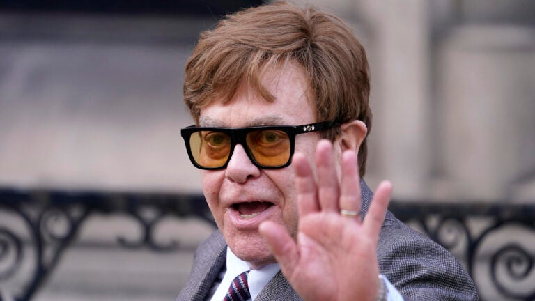 Elton John waves to the waiting media.