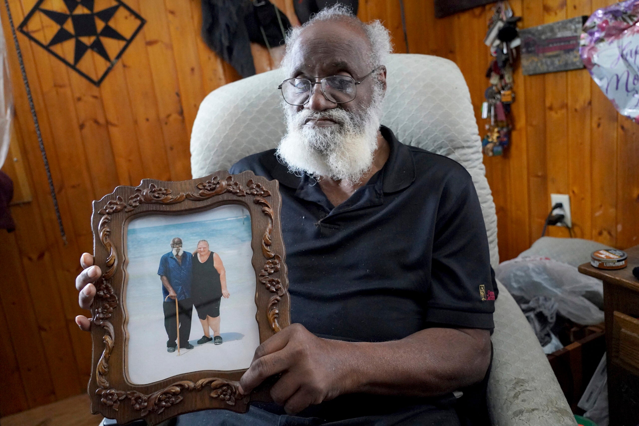 Kenny Pollard, 75 anos, segura uma foto em sua casa.
