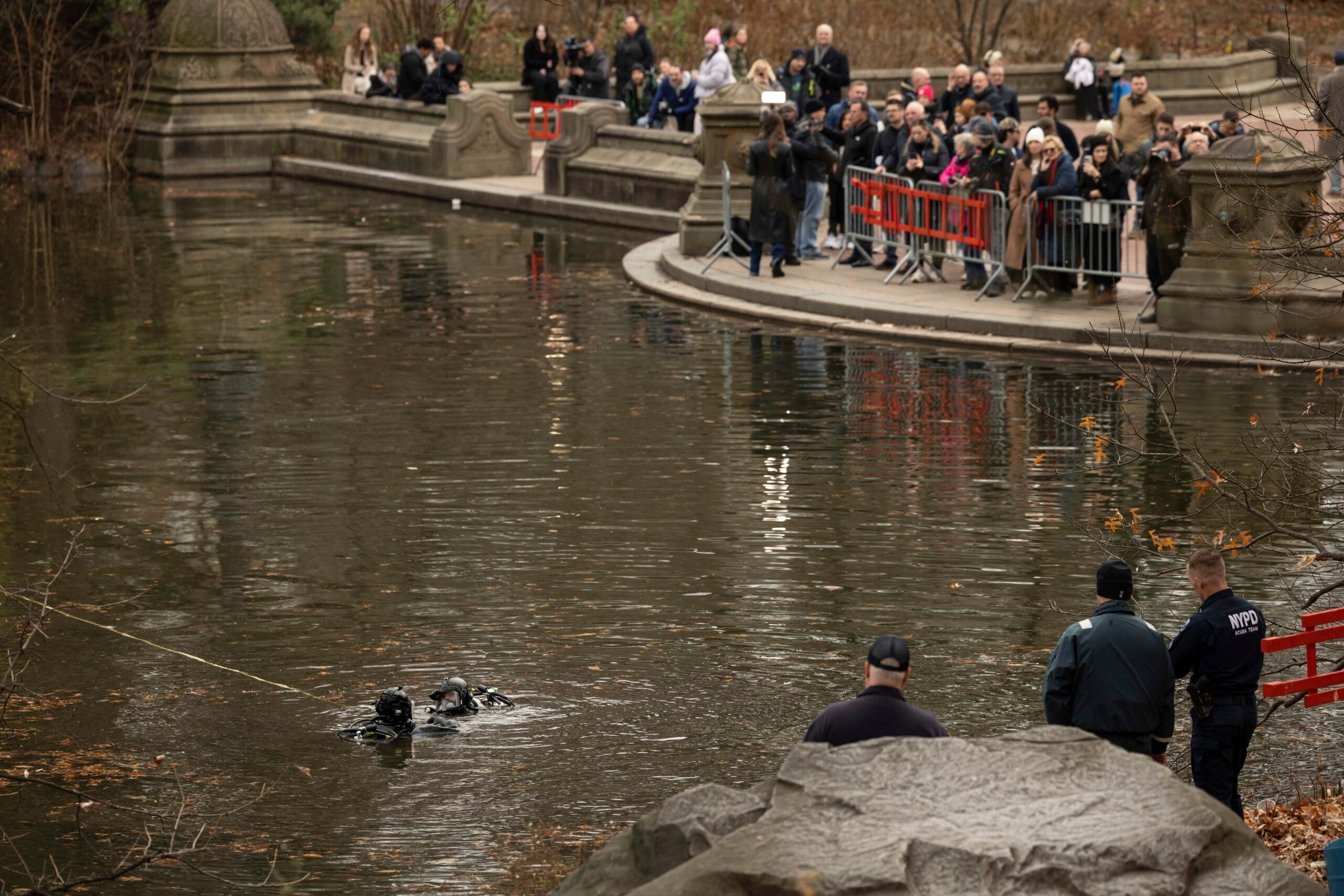 Policiais da NYPD em trajes de mergulho vasculham um lago no Central Park.
