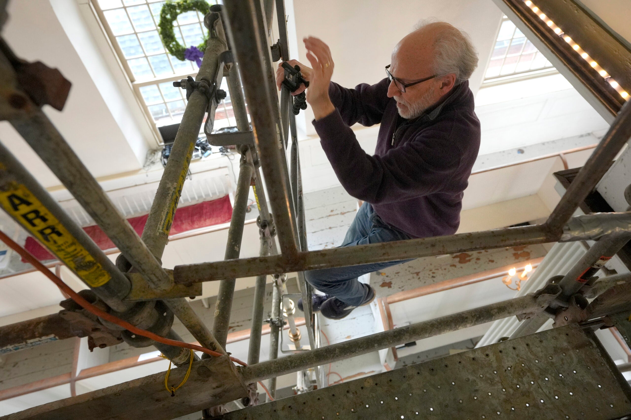 Conservator Gianfranco Pocobene, of Malden, Mass., climbs down scaffolding.