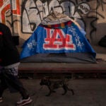 A man walks past a homeless encampment in downtown Los Angeles.