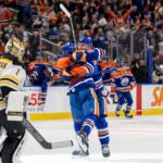 Edmonton Oilers' Mattias Ekholm (14) celebrates his overtime game-winning goal against Boston Bruins goalie Jeremy Swayman (1) with Ryan Nugent-Hopkins (93) during an NHL hockey game in Edmonton, Alberta, Thursday, Dec. 19, 2024.