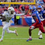Colorado wide receiver Travis Hunter (12) pushes away Kansas cornerback Mello Dotson (3) as he runs for a first down during the first half of an NCAA college football game, Saturday, Nov. 23, 2024, in Kansas City, Mo.