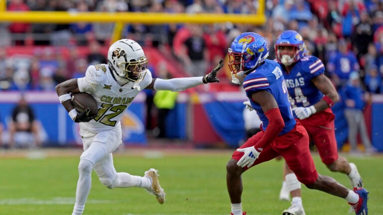 Colorado wide receiver Travis Hunter (12) pushes away Kansas cornerback Mello Dotson (3) as he runs for a first down during the first half of an NCAA college football game, Saturday, Nov. 23, 2024, in Kansas City, Mo.