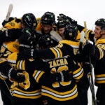 Players surround Boston Bruins center Pavel Zacha (18) after his goal in overtime at TD Garden.