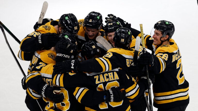 Players surround Boston Bruins center Pavel Zacha (18) after his goal in overtime at TD Garden.