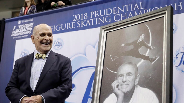 Dick Button smiles next to a painting of him.